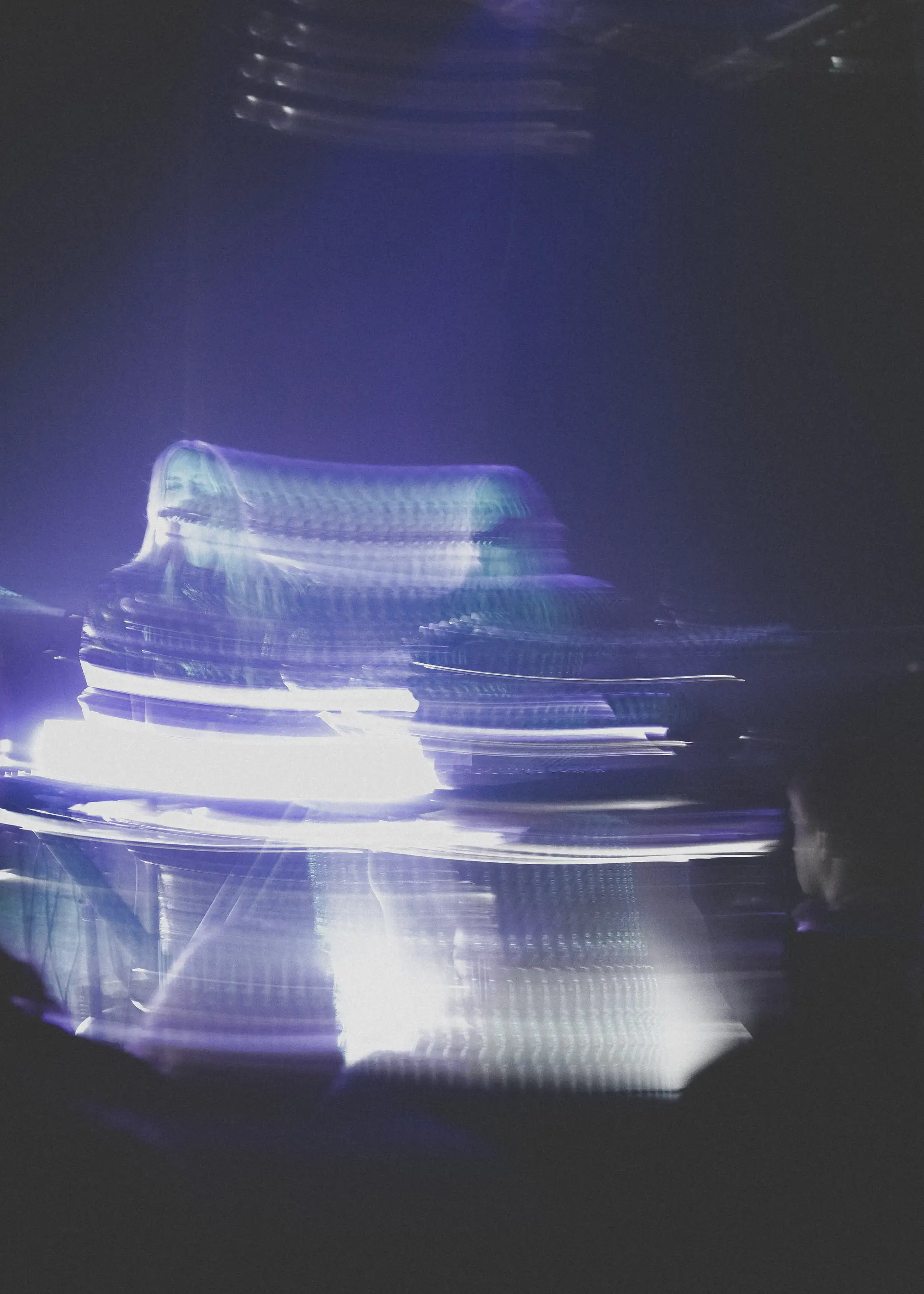 A long-exposure smear of violet light swallows a keyboardist