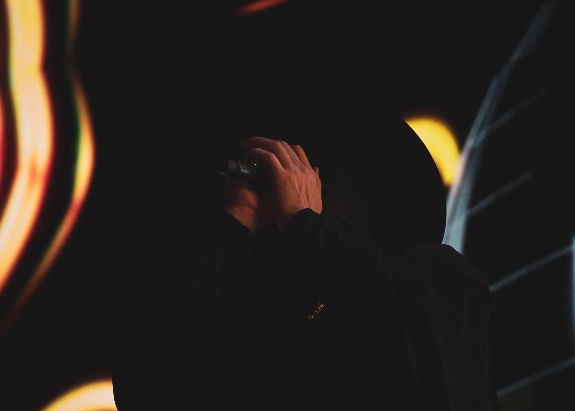A hand grips a microphone in darkness beside amber ember light