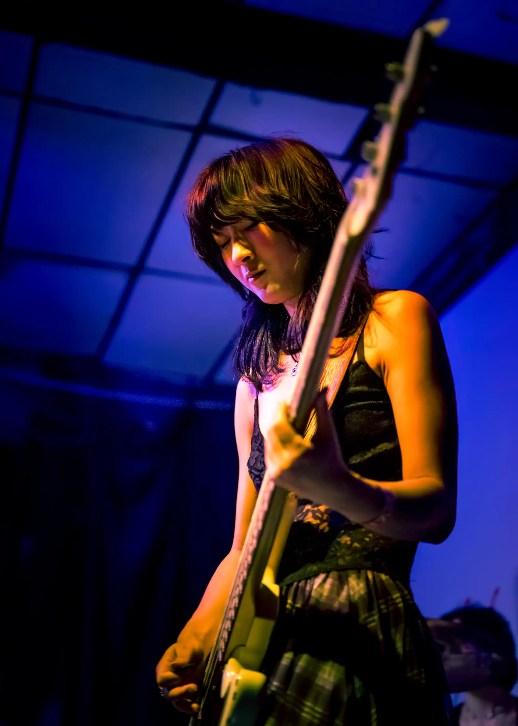 Bassist lit deep blue, head bowed over the strings