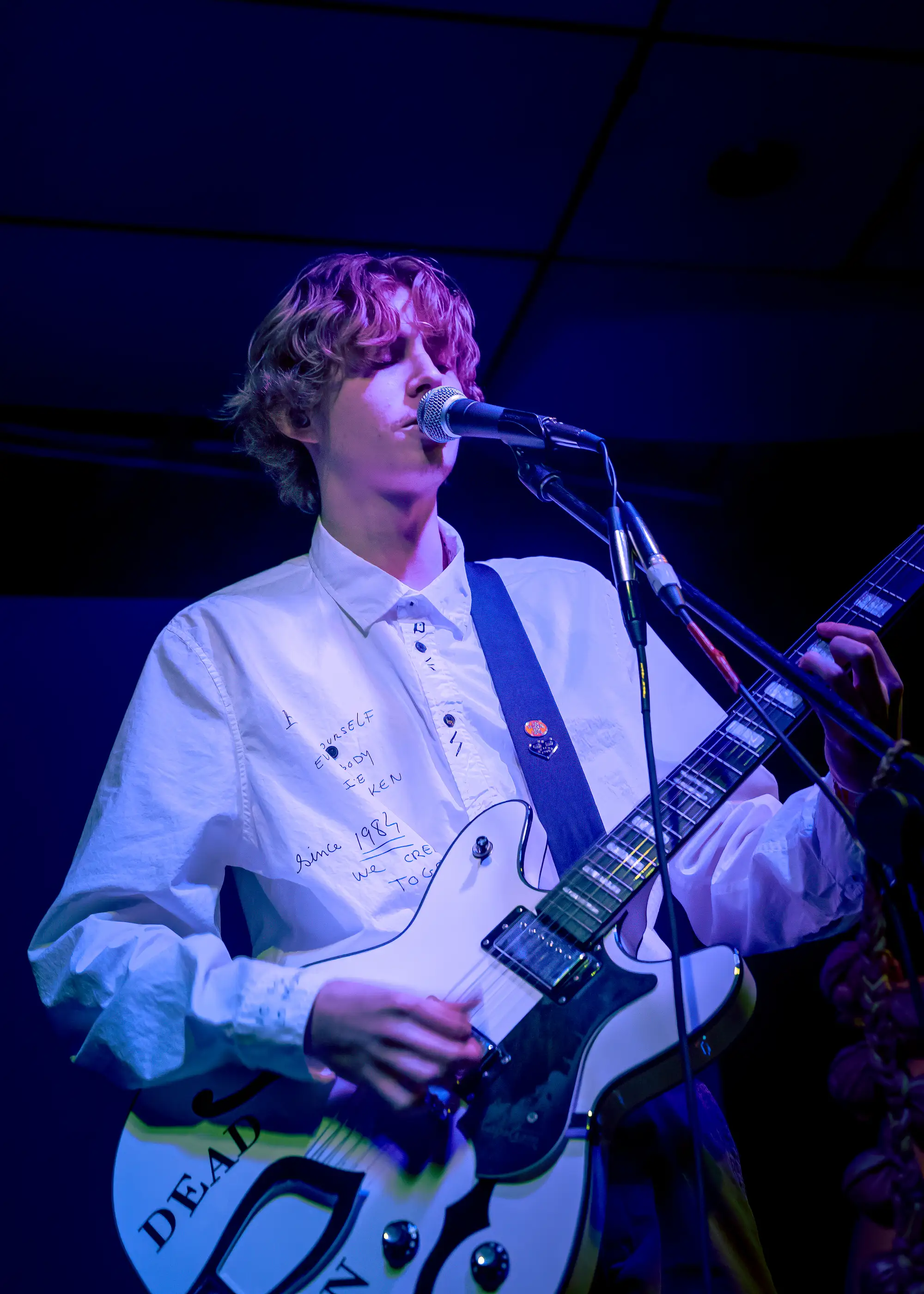 Singer with white guitar in blue and violet stage light