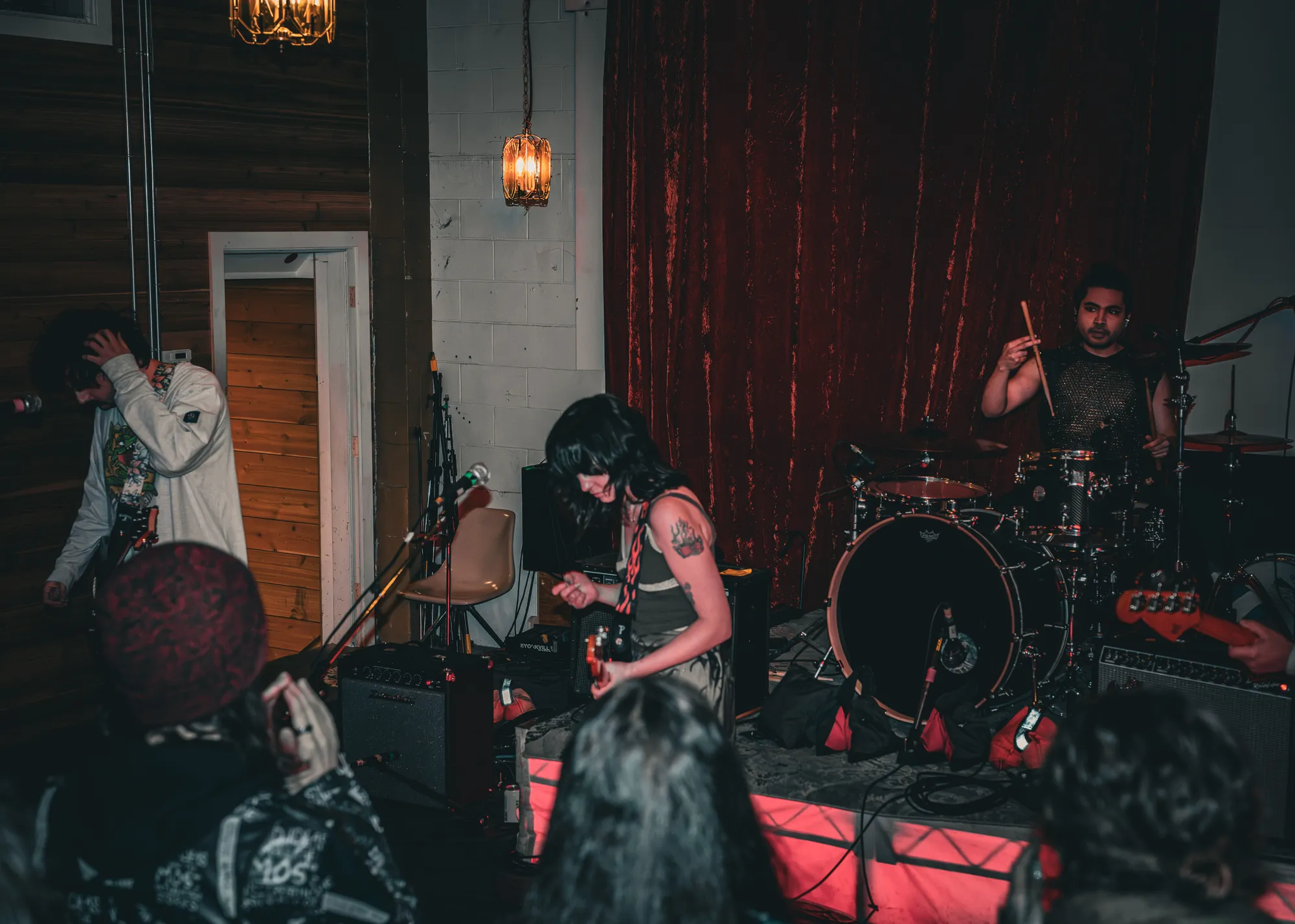Full stage under red velvet curtain, drummer mid-hit