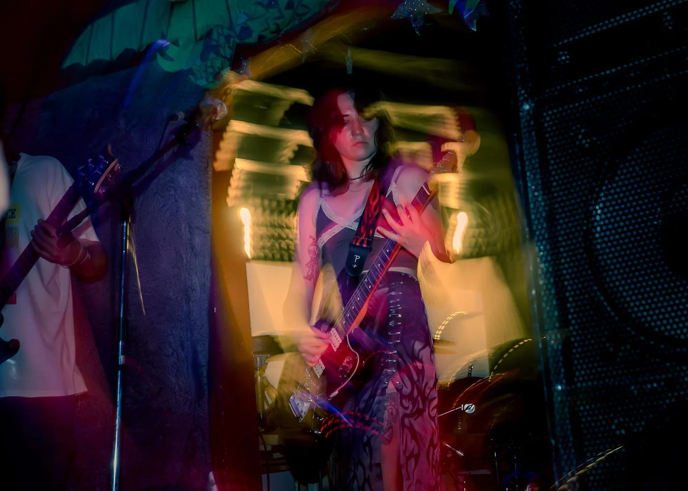 Guitarist dissolving into long-exposure blur under amber light