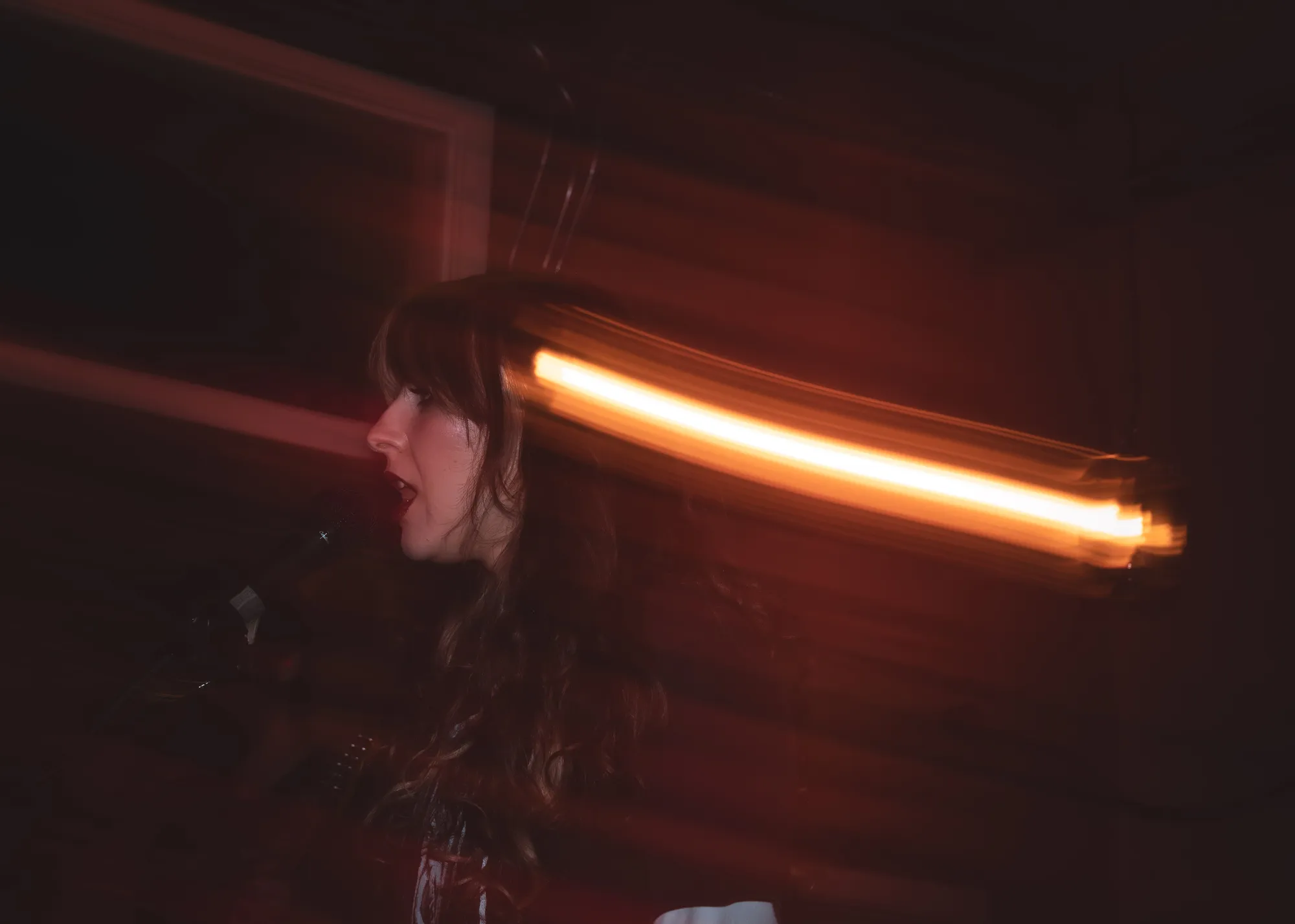 Vocalist in profile in near darkness with an amber light streak