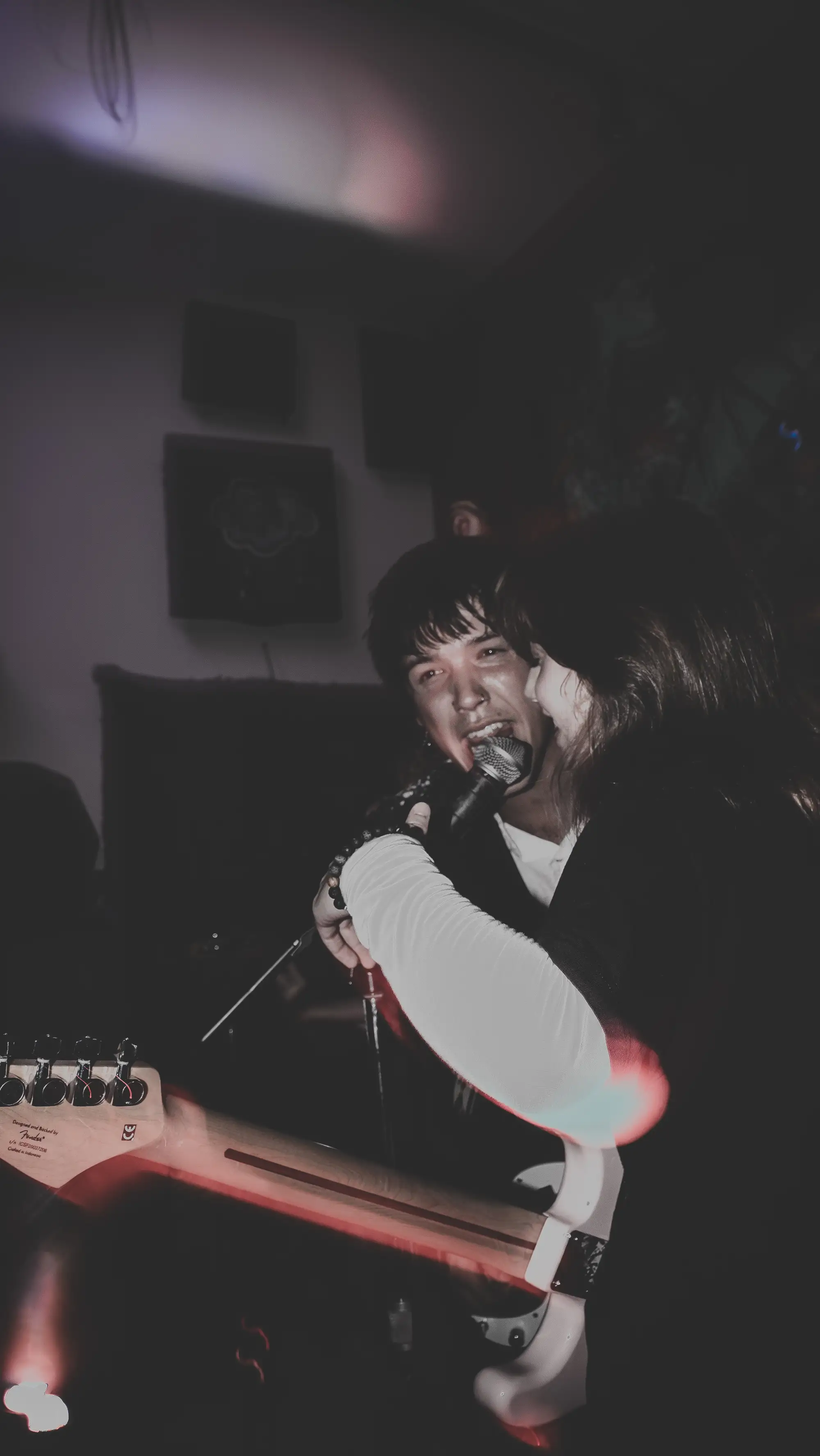 Singer screaming into a hand-held mic, washed-out and grim