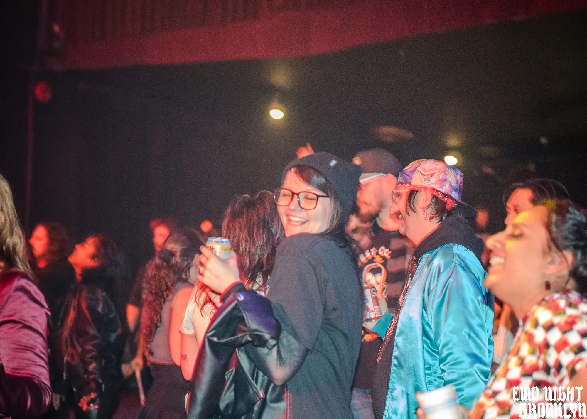 Grinning crowd hugging and dancing on the floor under red light