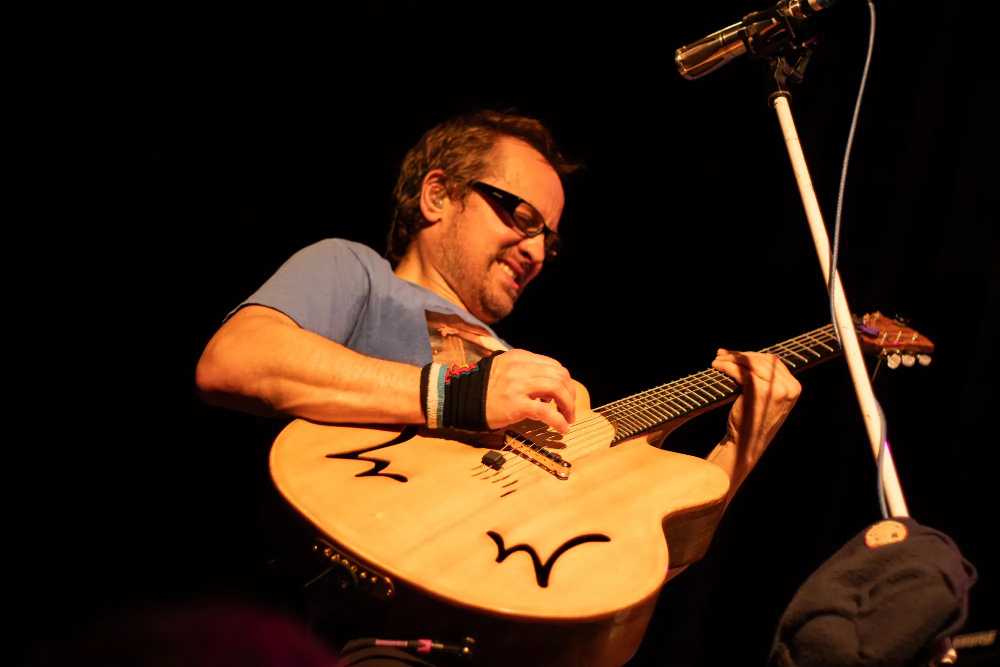 Guitarist grimacing joyfully over an acoustic guitar at the Pearl